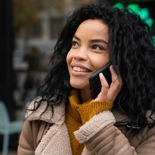 voyance audiotel sans CB Jeune femme métisse souriante en communication téléphonique pendant une voyance audiotel en ligne
